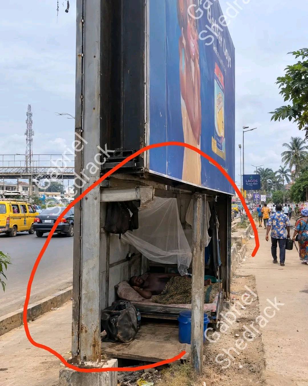 Lagos is truly not for the weak 😳 A man was spotted living under a billboard by the roadside.