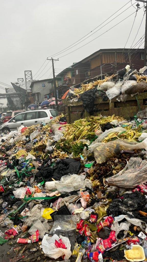 Images showing heaps of refuse dumped along a road in Oshodi, Lagos, occupying two lanes of the road...