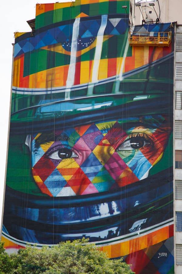 This image shows the vibrant 41-meter-high mural "A Lenda do Brasil" painted by renowned muralist Ed...